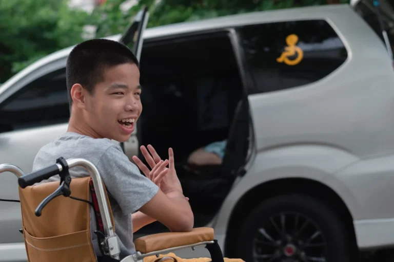 Disabled boy in wheelchair next to van