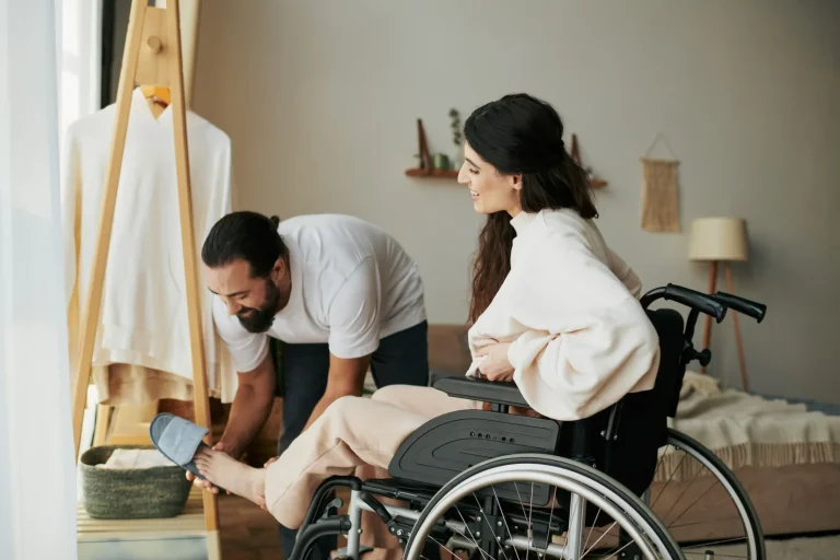 Support worker helping disabled woman put shoes on